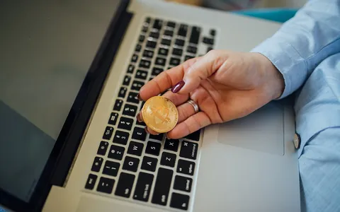 Bitcoin coin beside a laptop