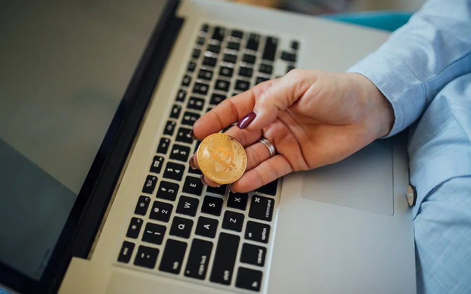 Bitcoin coin beside a laptop